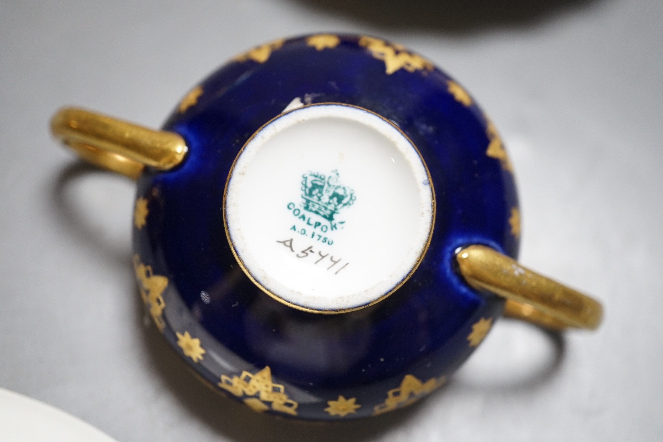 A 19th century Coalport fan shaped dish painted with a Loch scene, two small cup with twin handles decorated with raised gilding on a cobalt blue ground with crown marks, a Copeland jewelled cup and saucer with blue grou